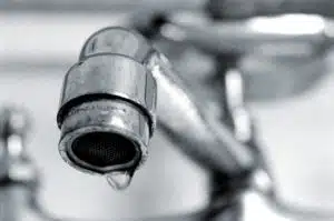 metal faucet in sink of residential bathroom. Dripping water.