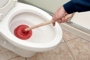 A plumber uses a plunger to unclog a toilet