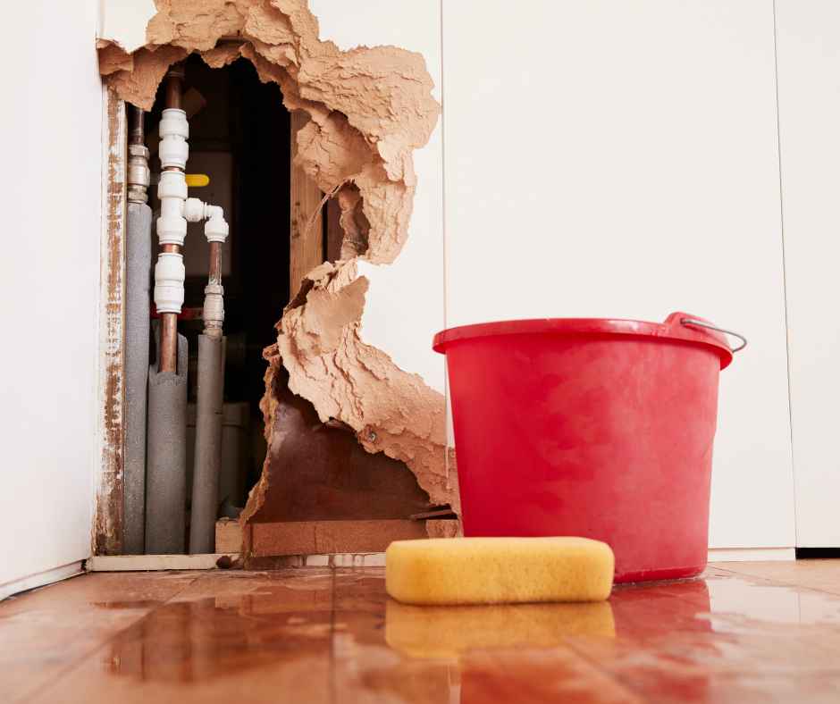 Hole in the wall revealing a plumbing emergency with pipes